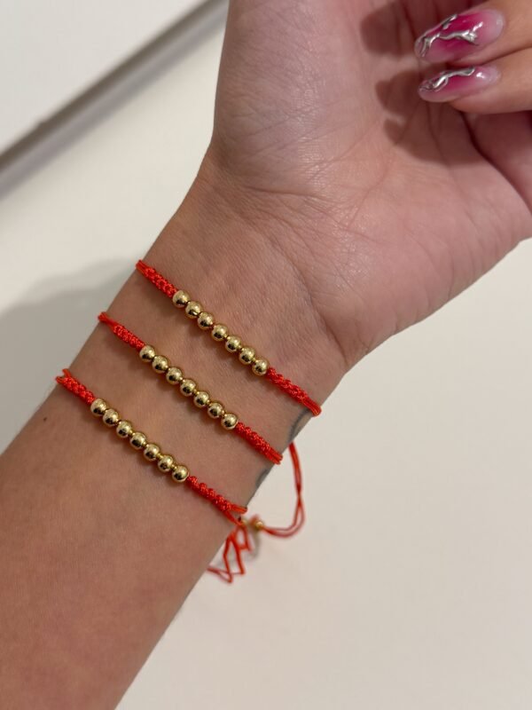 Pulsera hilo rojo balls acero dorado